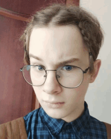 a young man wearing glasses and a plaid shirt