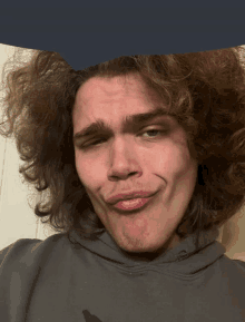 a young man with curly hair makes a funny face