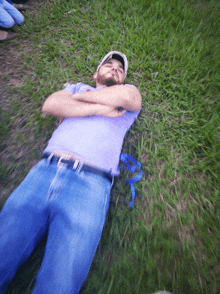 a man in a purple shirt is laying in the grass