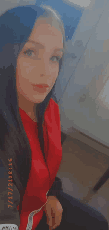 a woman wearing a red jacket is taking a selfie on 7/11/2021