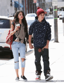 a man and a woman walking down a sidewalk with a parking sign in the background