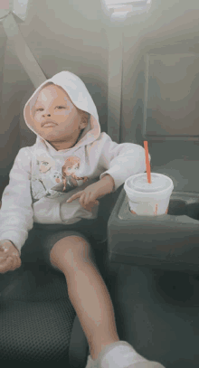 a little girl wearing a frozen sweatshirt sits in a car