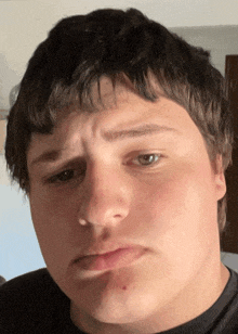 a close up of a man 's face with a black shirt on