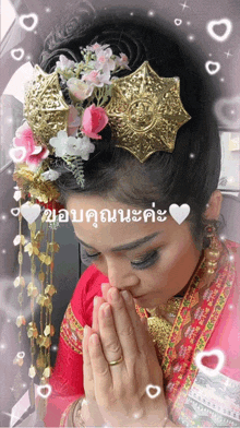 a woman wearing a red dress and a gold headpiece is praying with her hands folded in front of her face