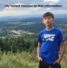 a boy in a blue nike shirt stands in front of a mountain