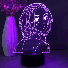 a night light with a picture of a person on it is sitting next to a vase with flowers .