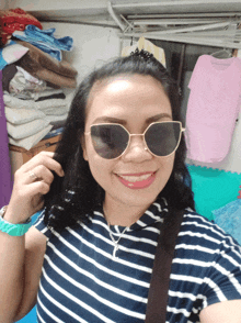 a woman wearing sunglasses and a striped shirt takes a selfie