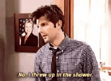 a man in a plaid shirt and tie is throwing up in the shower