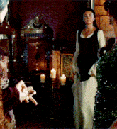 a woman in a black and white dress stands in front of a candle