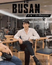 a poster for busan shows a man sitting at a table