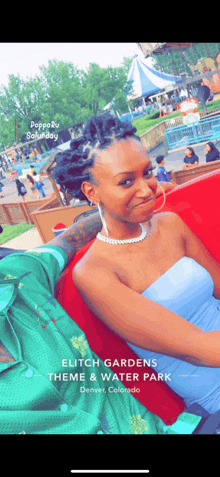 a woman in a blue dress is sitting in a red chair at elite gardens theme & water park