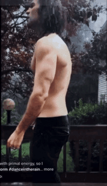 a shirtless man is standing on a deck in the rain .