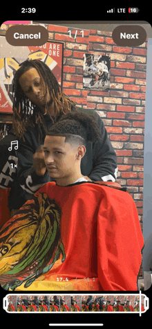 a man is getting his hair cut by a barber with a red cape on