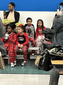 a group of children are sitting on a bench and one of them is wearing a santa claus pajama