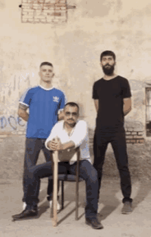 a man in a blue adidas shirt sits in a chair