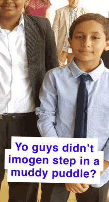 a boy in a blue shirt and tie stands next to another boy in a suit