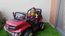 a baby is sitting in a red toy car with a license plate that says ln-028