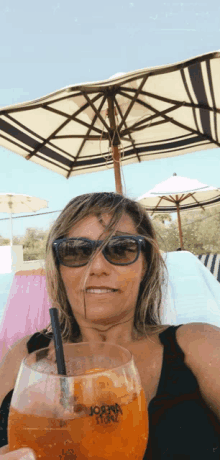 a woman sitting under an umbrella holding a glass that says joanna