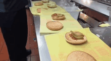 a bunch of hamburgers are sitting on a yellow paper on a counter .