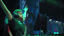 a man wearing headphones is raising his arms in the air in front of a monitor