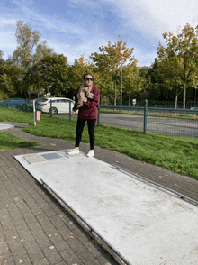 a woman wearing a sweatshirt that says " new york " is playing mini golf