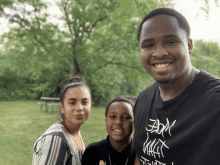 a man wearing a black shirt that says ' boom ' on it poses for a picture with his wife and son