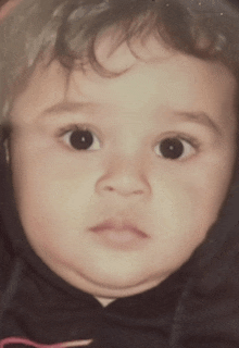 a close up of a baby 's face with a black hoodie on