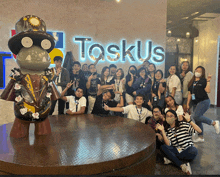 a group of people posing for a picture in front of a sign that says toskus