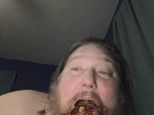 a man with a beard is eating a slice of pizza