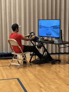 a man sits in a chair playing a video game on a monitor