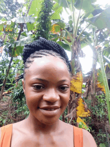 a woman with braids on her head is smiling in front of a tree