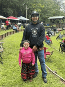 a man and a little girl are standing in a grassy field .