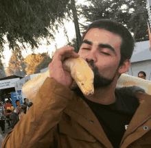 a man with a beard holds a snake in his mouth in front of a sign that says ' universidad '