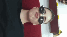 a boy wearing sunglasses and a black shirt making a funny face