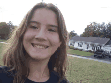 a young woman smiles in front of a house