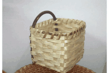 a small basket with a wooden handle is sitting on a wicker basket