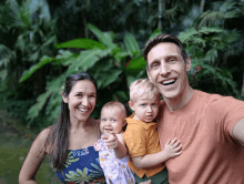 a family posing for a picture with a baby pointing to the camera