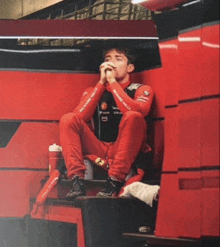 a man wearing a red richard mille shirt sits on a red bench