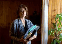 a woman is standing in a doorway holding a bunch of papers .