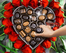 a heart shaped box of chocolates surrounded by red roses with the word all love written on it