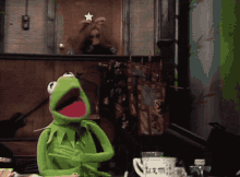 kermit the frog is sitting at a table with a star in his hand