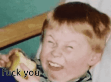 a young boy is eating a banana and making a funny face with the words fuck you above him