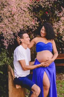 a pregnant woman in a blue dress is sitting next to a man in a white shirt