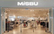 the inside of a misbu store with a lot of clothes on display