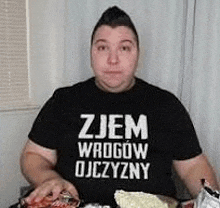 a man in a black shirt is sitting at a table eating food .