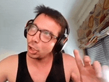 a man wearing headphones and glasses is making a funny face while talking on a video call .