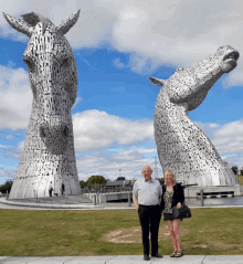 a man and a woman are standing in front of a statue of a horse