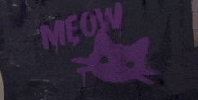 a purple cat is painted on a black surface with the words meow written on it .