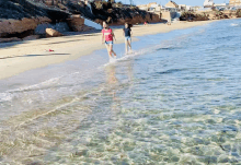 two people walking on a beach with one wearing a red shirt that says ' i love you ' on it