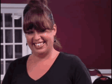 a woman wearing a black shirt and earrings smiles for the camera